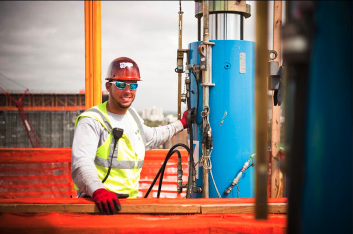 PT Pros crew member operating a multi-strand stressing jack on a high-rise jobsite
